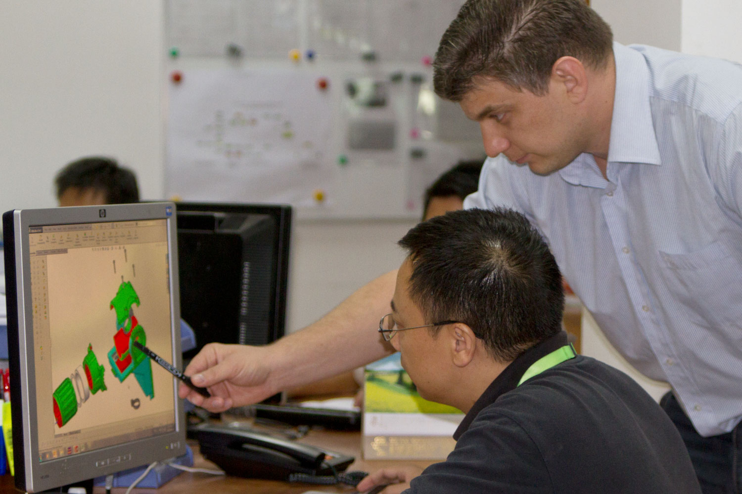 Research and development department in Tetro, China, 2 men near a computer looking at a 3D part